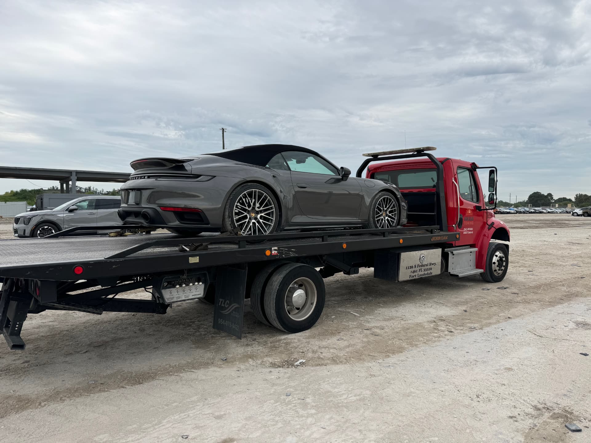 High Solar Towing red flatbed truck transporting a Porsche in South Florida
